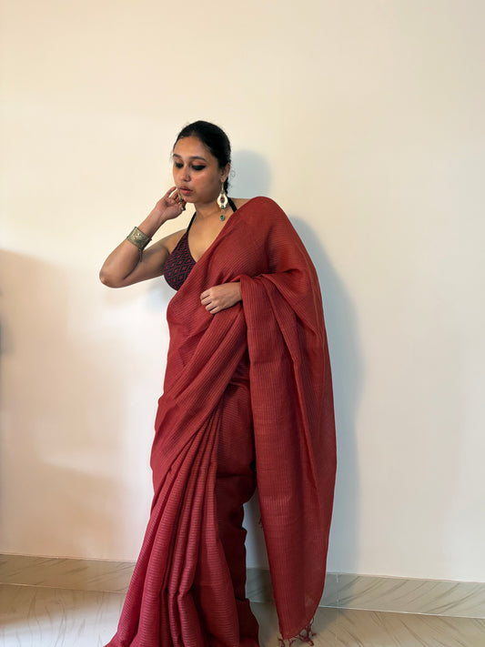 Woman wearing a red saree against a plain background