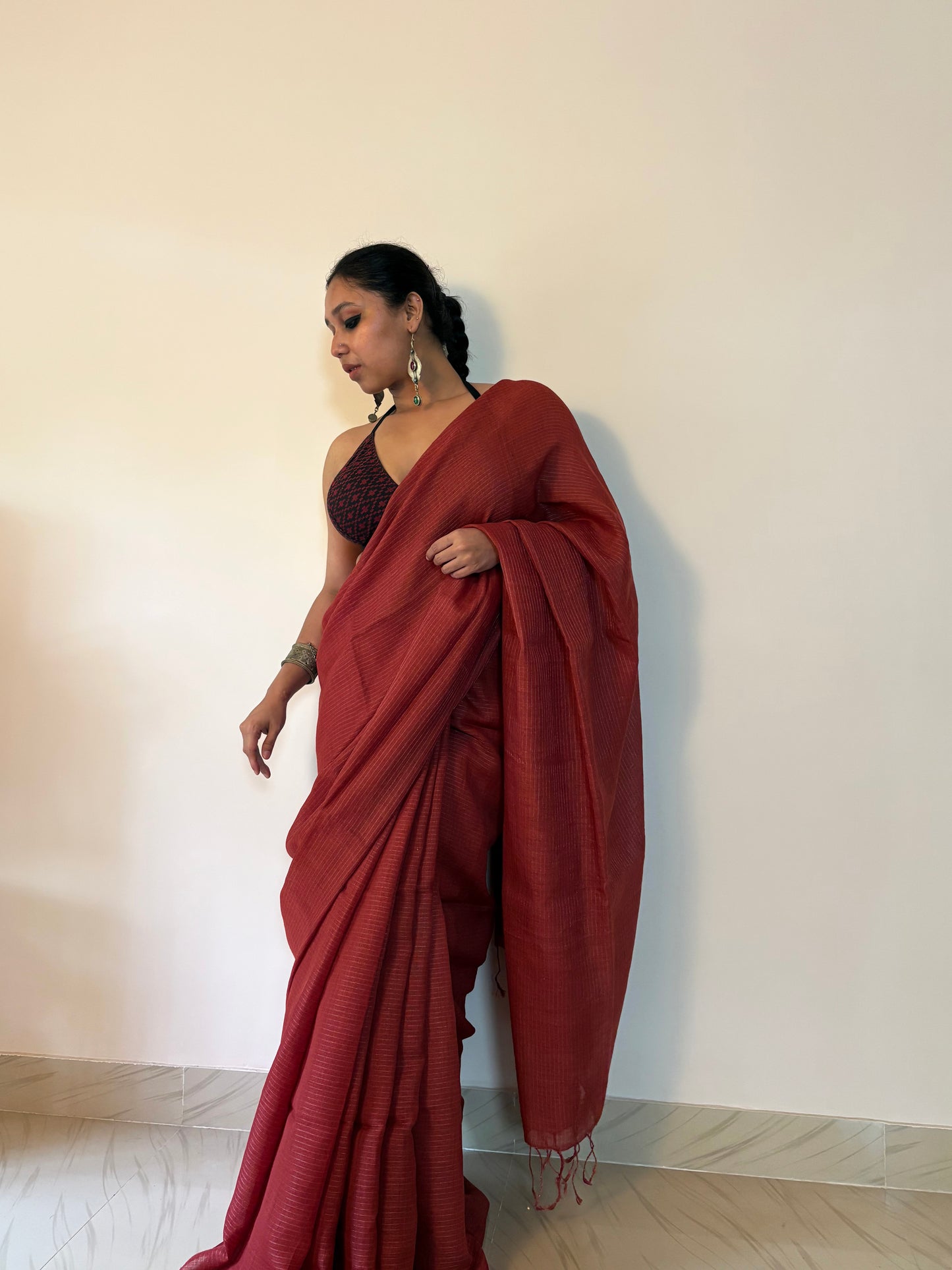 Woman wearing a red saree against a plain background