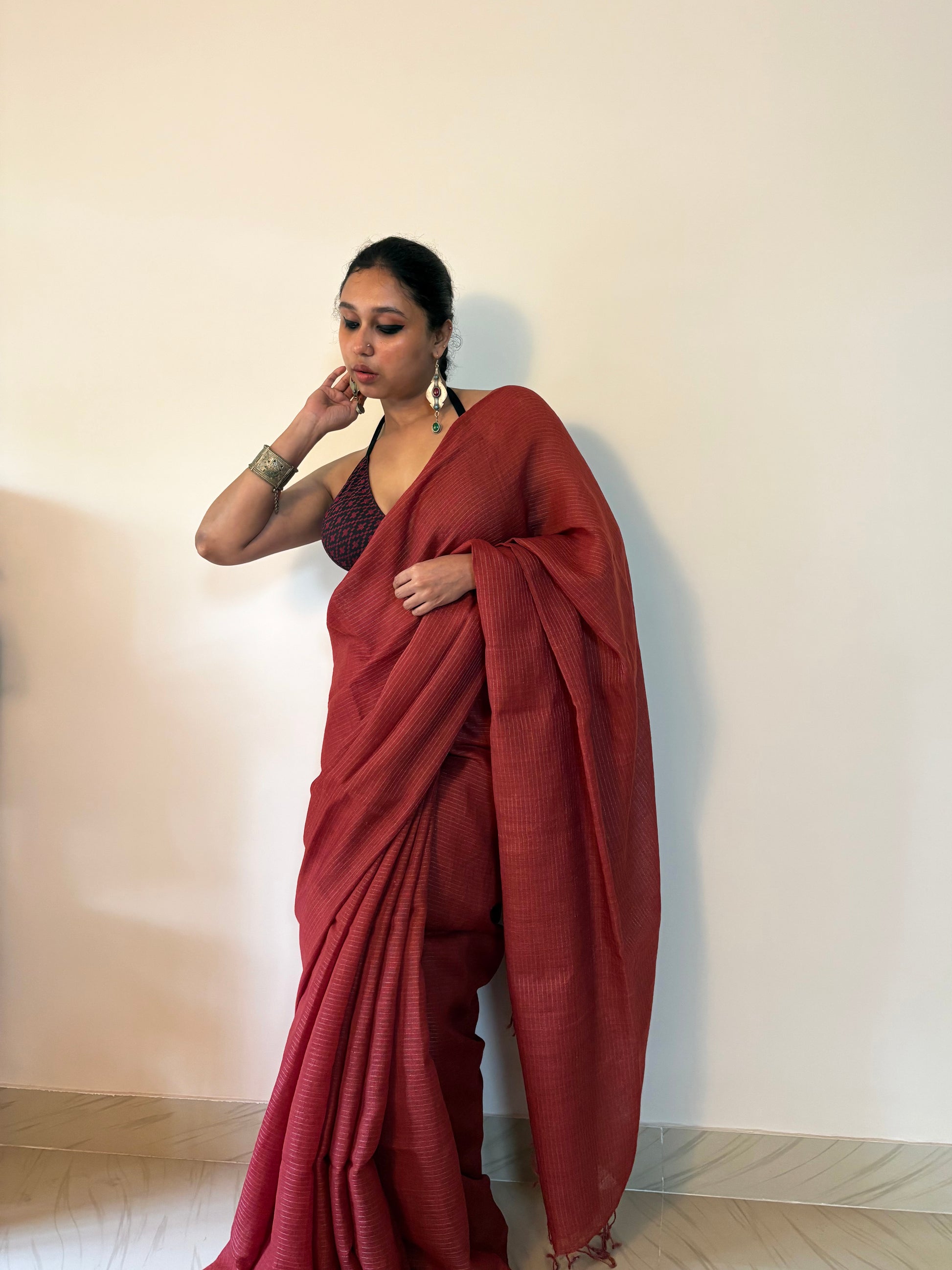 Woman wearing a red saree against a plain background